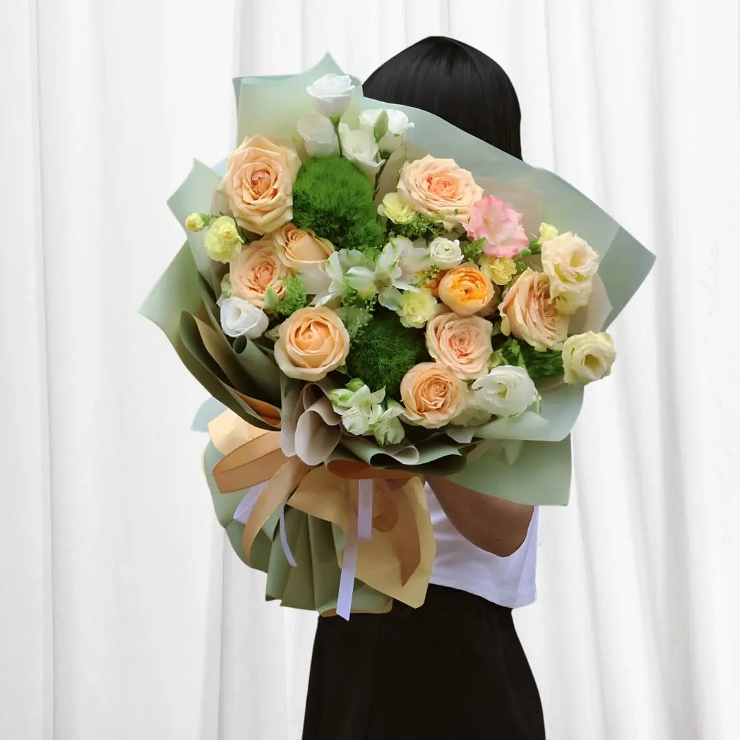 Peach Blossom Elegance Bouquet featuring peach roses, ranunculus, lisianthus, baby's breath, and greenery arranged in a delicate, romantic style.