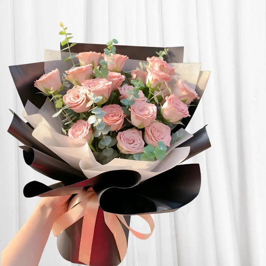 Rosy Elegance Bouquet with 18 pink roses, eucalyptus leaves, black and white wrap, and peach ribbon.